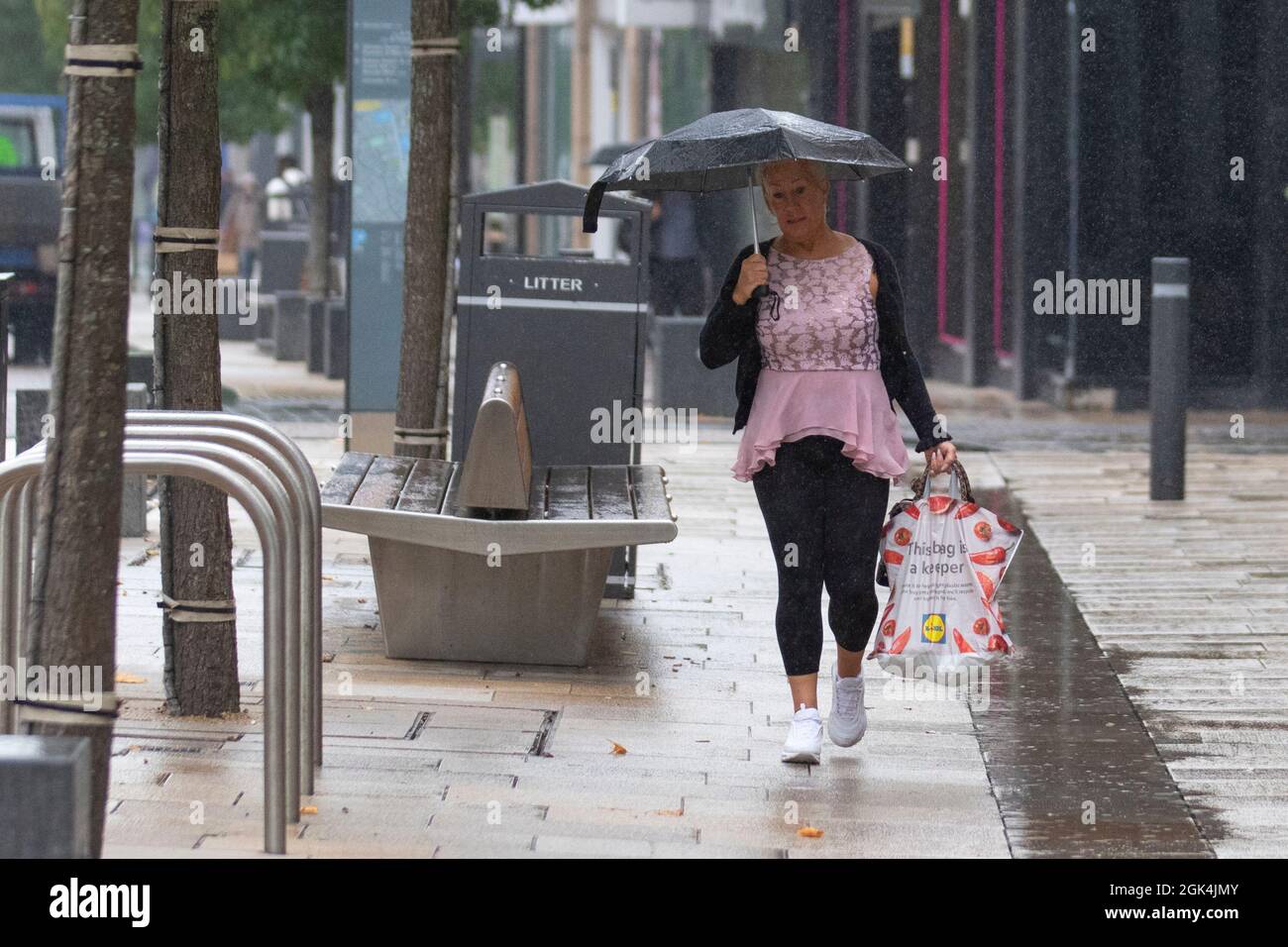 Woman with shooping bags and umbrellas on wet day in Preston, Lancashire.  UK Weather. Sept 2021.  Shops, shoppers shopping on a rainy day in the city centre. Credit; MediaWorldImages/AlamyLiveNews Stock Photo