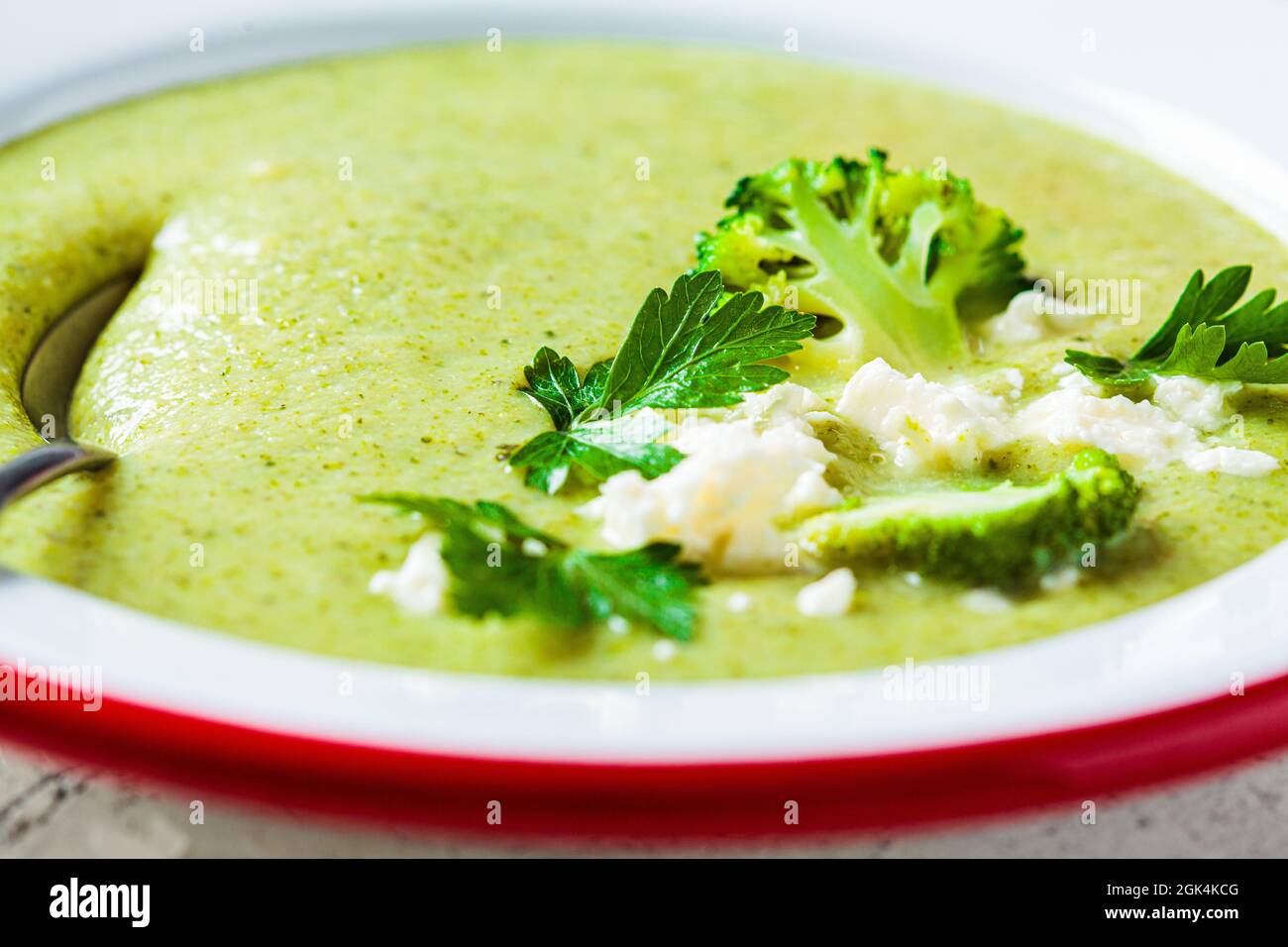 Broccoli soup puree with feta cheese in white plate, close-up. Cooking healthy food concept. Stock Photo