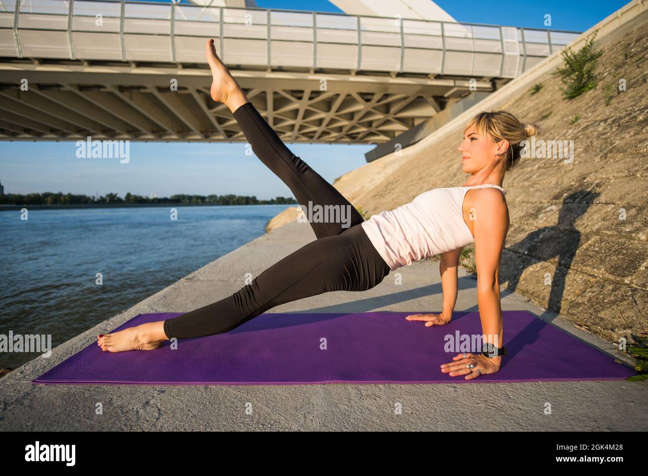 Young woman is exercising outdoor. She is practicing pilates. Leg