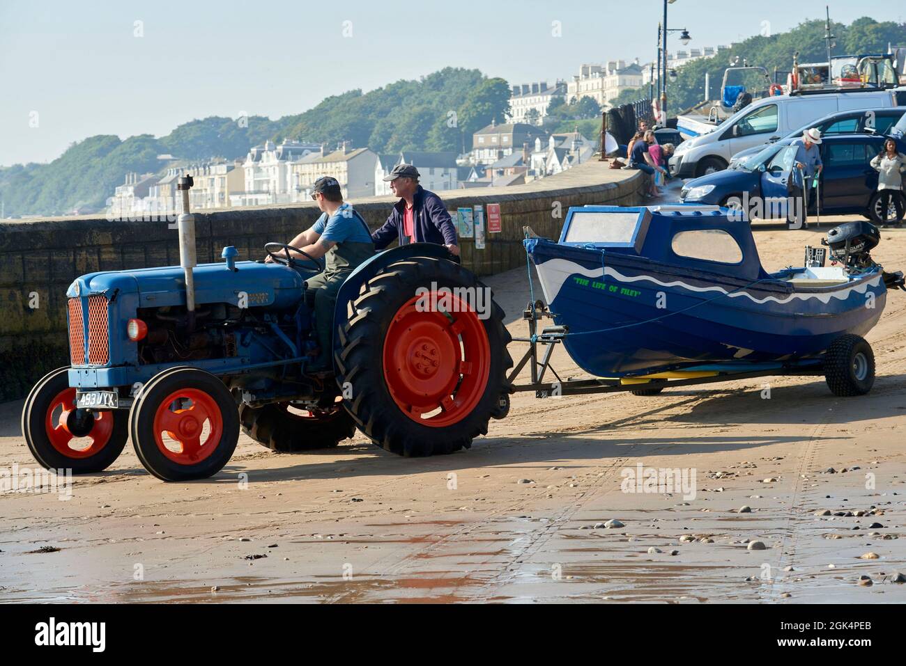 Old tractor used for launching fishing boats Fishing boats at Filey Beach, North Yorkshire east coast, busy with holiday makers, Northern England, UK Stock Photo