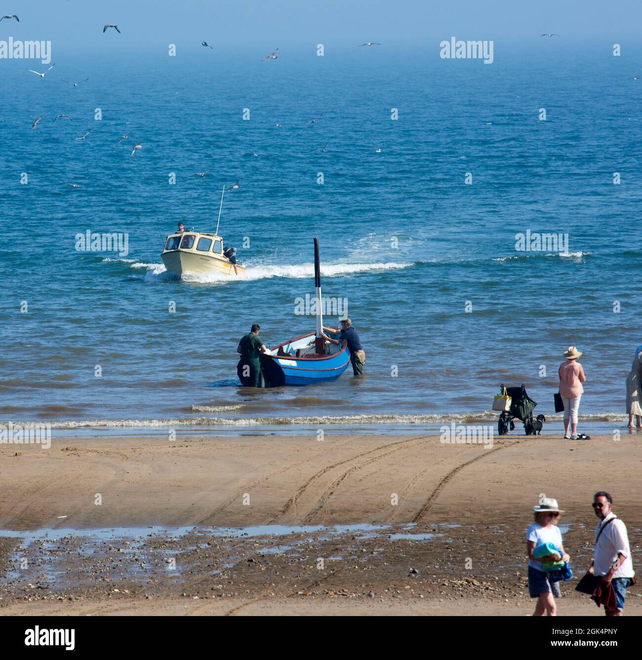 Fishing boats coming back home at Filey Beach, North Yorkshire east coast, busy with holiday makers, Northern England, UK Stock Photo