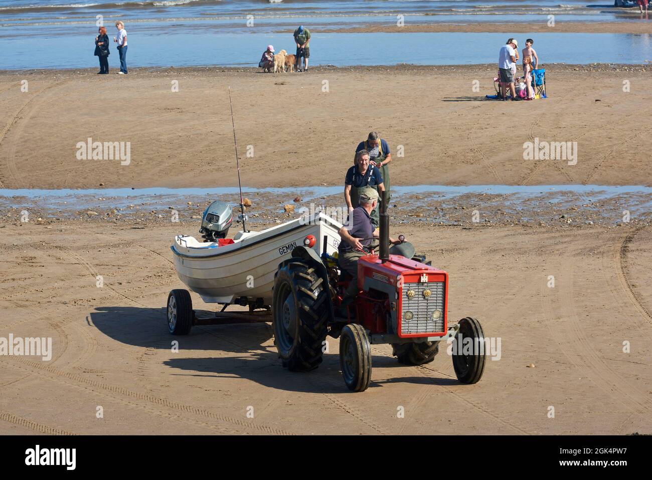 Old tractor used for launching Fishing boats at Filey Beach, North Yorkshire east coast, busy with holiday makers, Northern England, UK Stock Photo