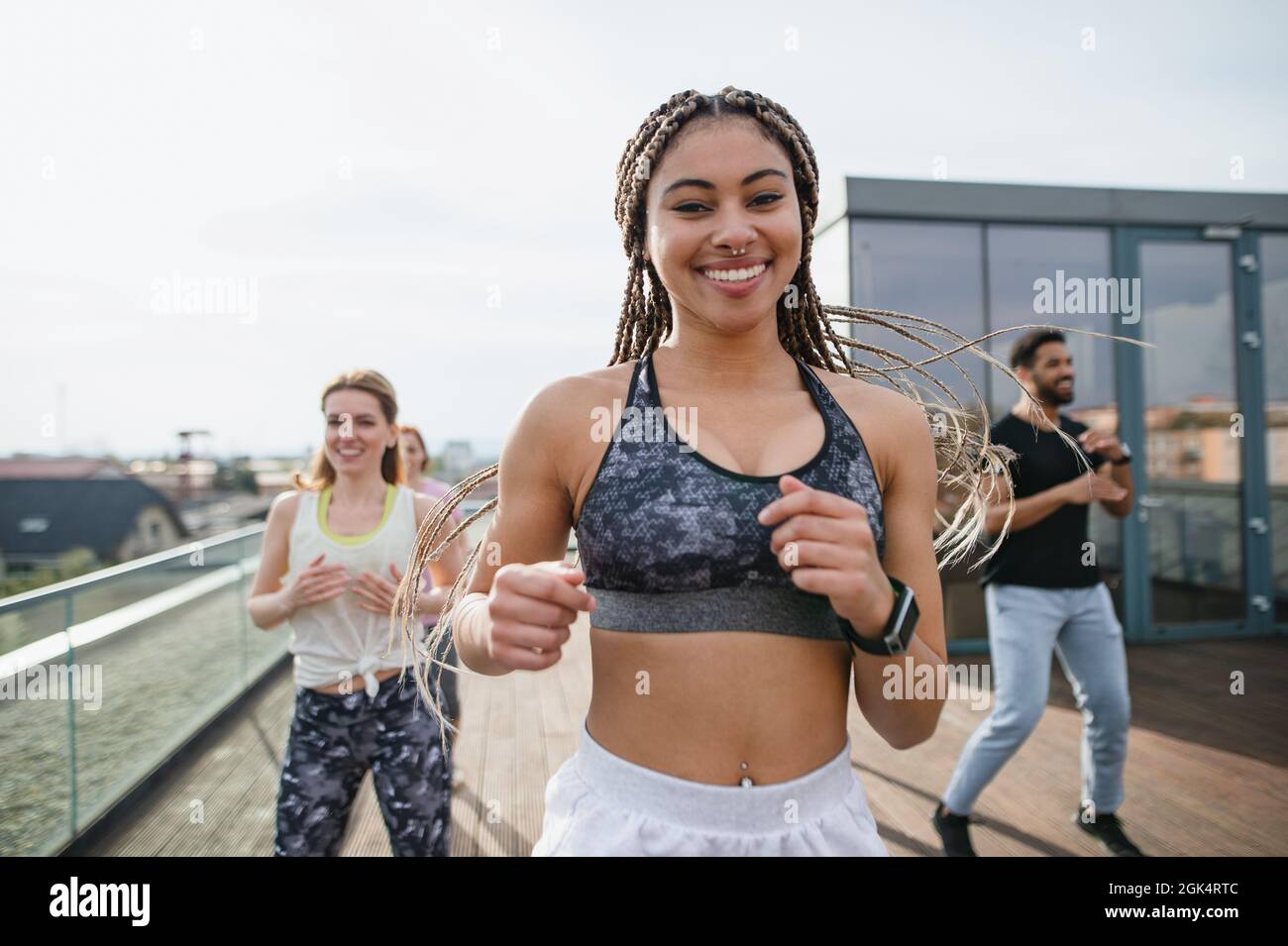 Group of young people doing exercise outdoors on terrace, sport and healthy lifestyle concept. Stock Photo