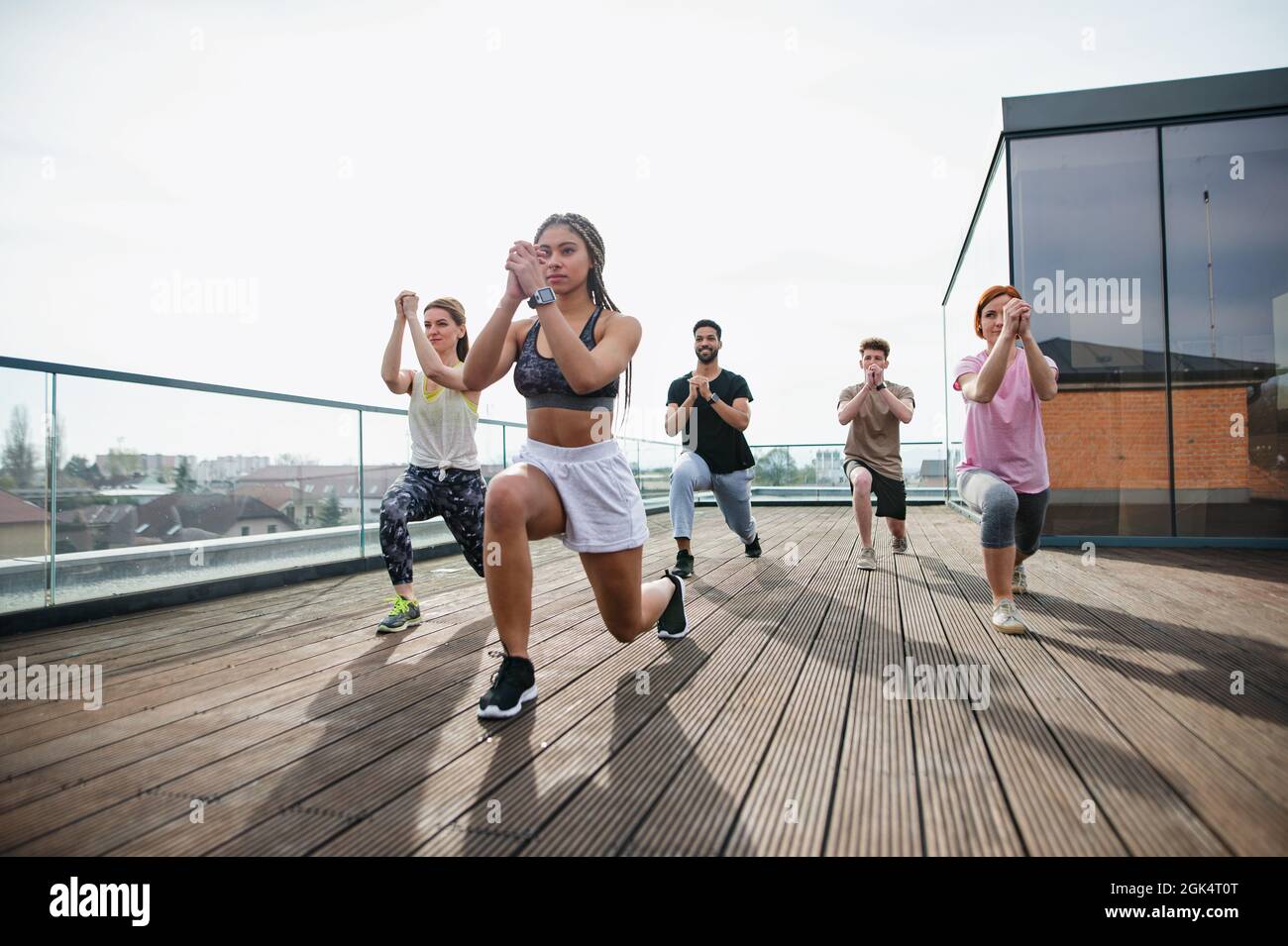 Group of young people doing exercise outdoors on terrace, sport and healthy lifestyle concept. Stock Photo