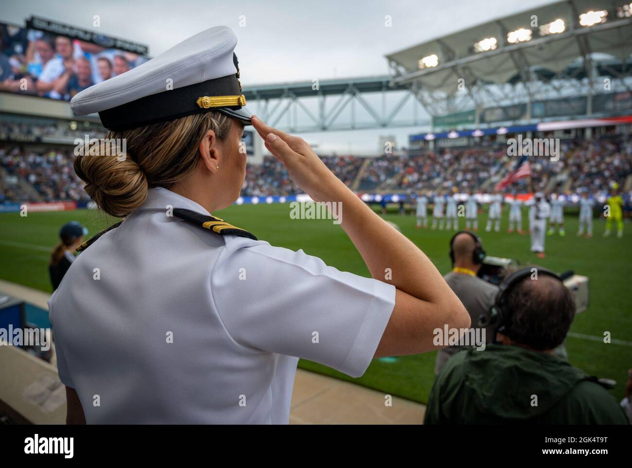 210801-N-WF272-1255 CHESTER, Pa. (Aug. 1, 2021) Lt. Taylor VanderWoude,  from Boston, a medical officer programs recruiter at Navy Talent  Acquisition Group Philadelphia, salutes during the national anthem at a  Philadelphia Union's soccer