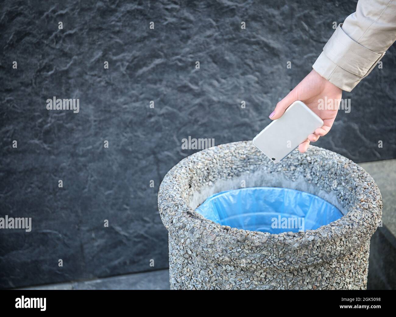Woman throwing phone into stone bin on street Stock Photo Alamy