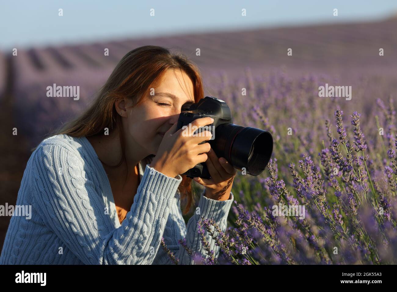 Woman photographing lavender flowers with dslr camera in a beautiful field Stock Photo