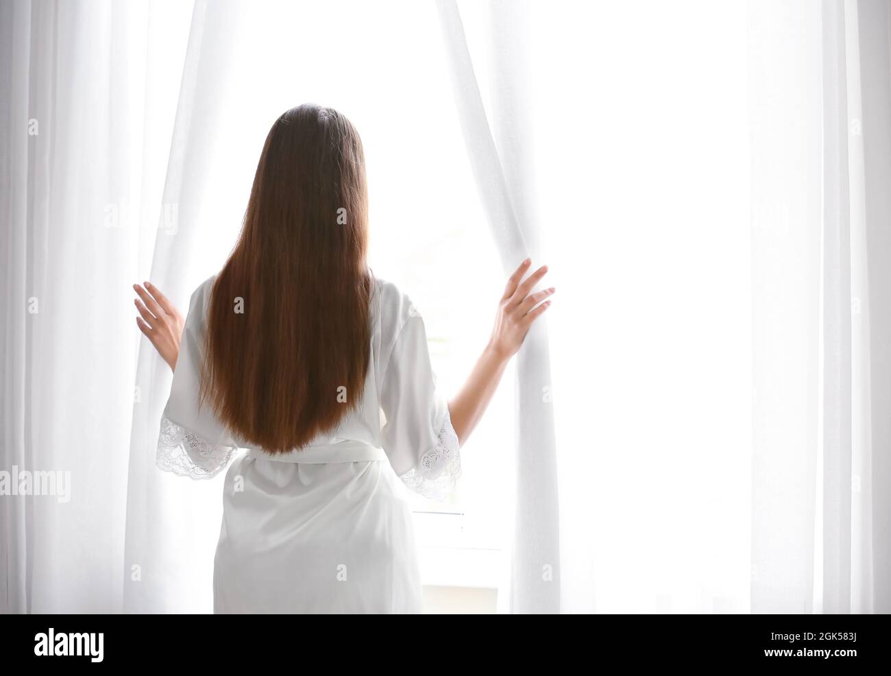 Young woman looking out the window at home Stock Photo - Alamy