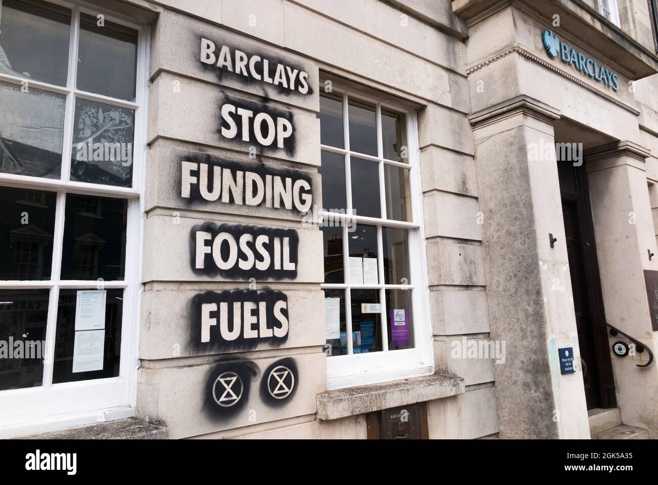 Graffiti including the extinction rebellion logo, written on a Barclays Bank wall, protesting about the use of fossil fuel is which cause global warming and climate change. Lewes in East Sussex, UK. (127) Stock Photo