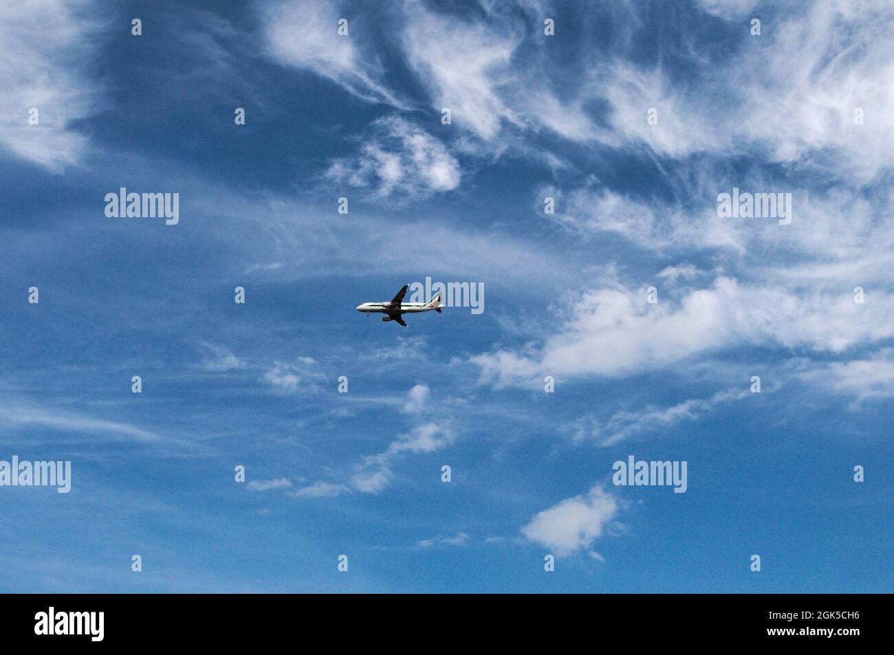 Plane Flying In Blue Sky With Clouds Stock Photo