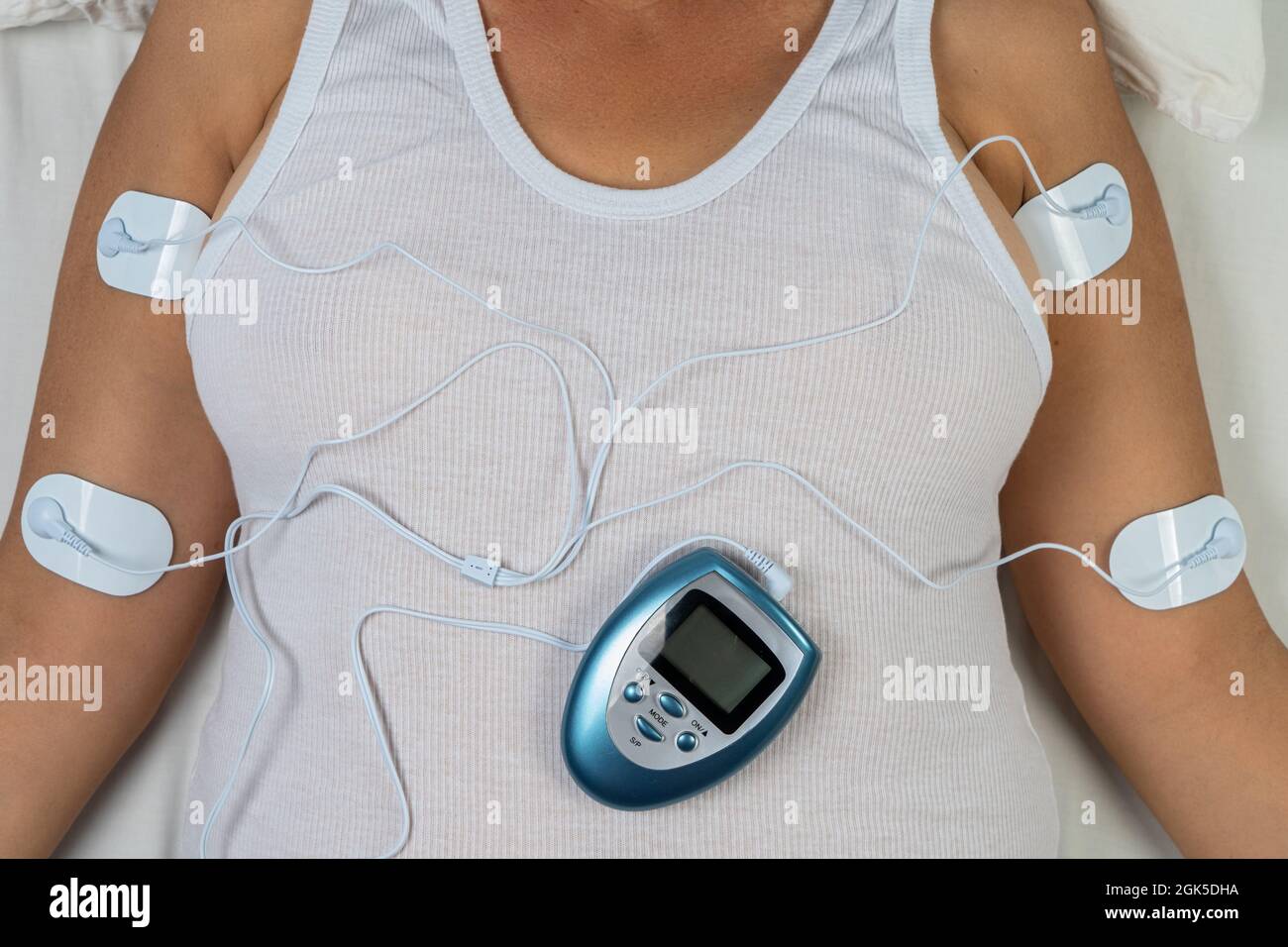 Woman lying on her back with four sensors that connect her to an electro massage equipment Stock Photo