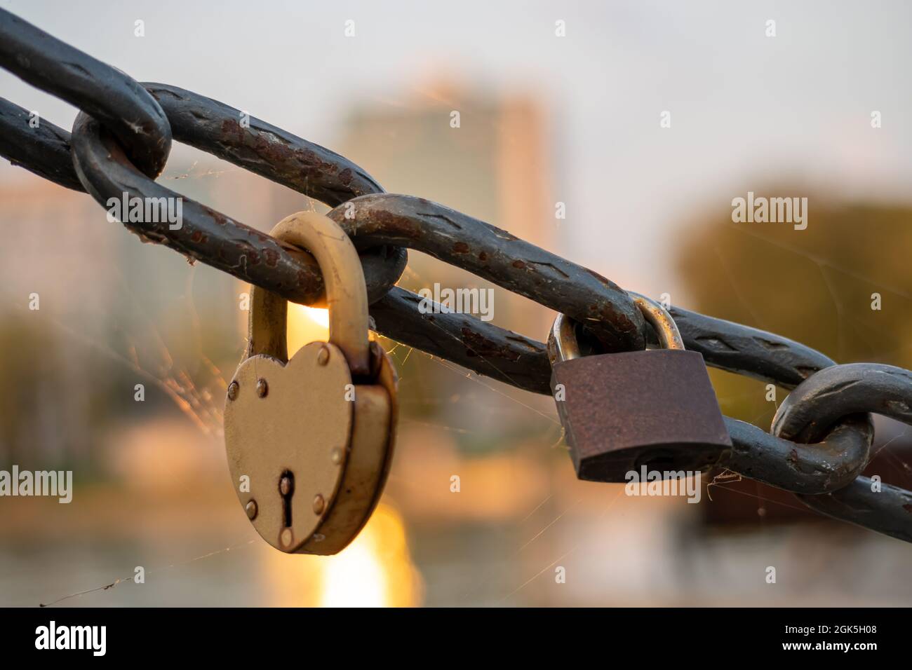 Rusty lovers locks on a chain on a bridge, lovers locks on a bridge chain Stock Photo