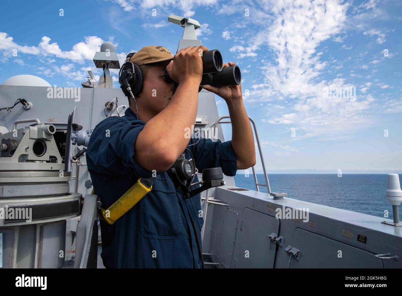 210808-N-PC065-1013 ATLANTIC OCEAN (Aug. 8, 2021) U.S. Navy Boatswain's Mate  3rd Class Jorge Perez, assigned to San Antonio-class amphibious transport  dock ship USS Arlington (LPD 24), looks through binoculars while standing  watch