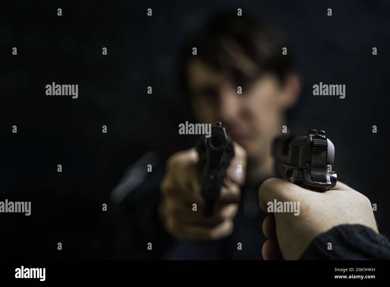 Man's hand with pistol pointed at criminal with revolver. Shootout of two thieves or murderers. Firearms for attack or defense. Stock Photo
