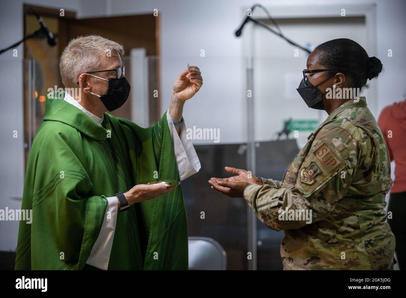 U.S. Air Force Chaplain Maj. Thomas Duston, deputy wing chaplain, 380th Air Expeditionary Wing, distributes communion to Staff Sgt. Deja Adams, 380th Expeditionary Logistics Readiness Squadron, during Mass at Al Dhafra Air Base, United Arab Emirates, Aug 8, 2021. ADAB’s unique chapel team is comprised of three different religious leaders and offers Jewish, Catholic and Protestant services and events throughout the week. Stock Photo