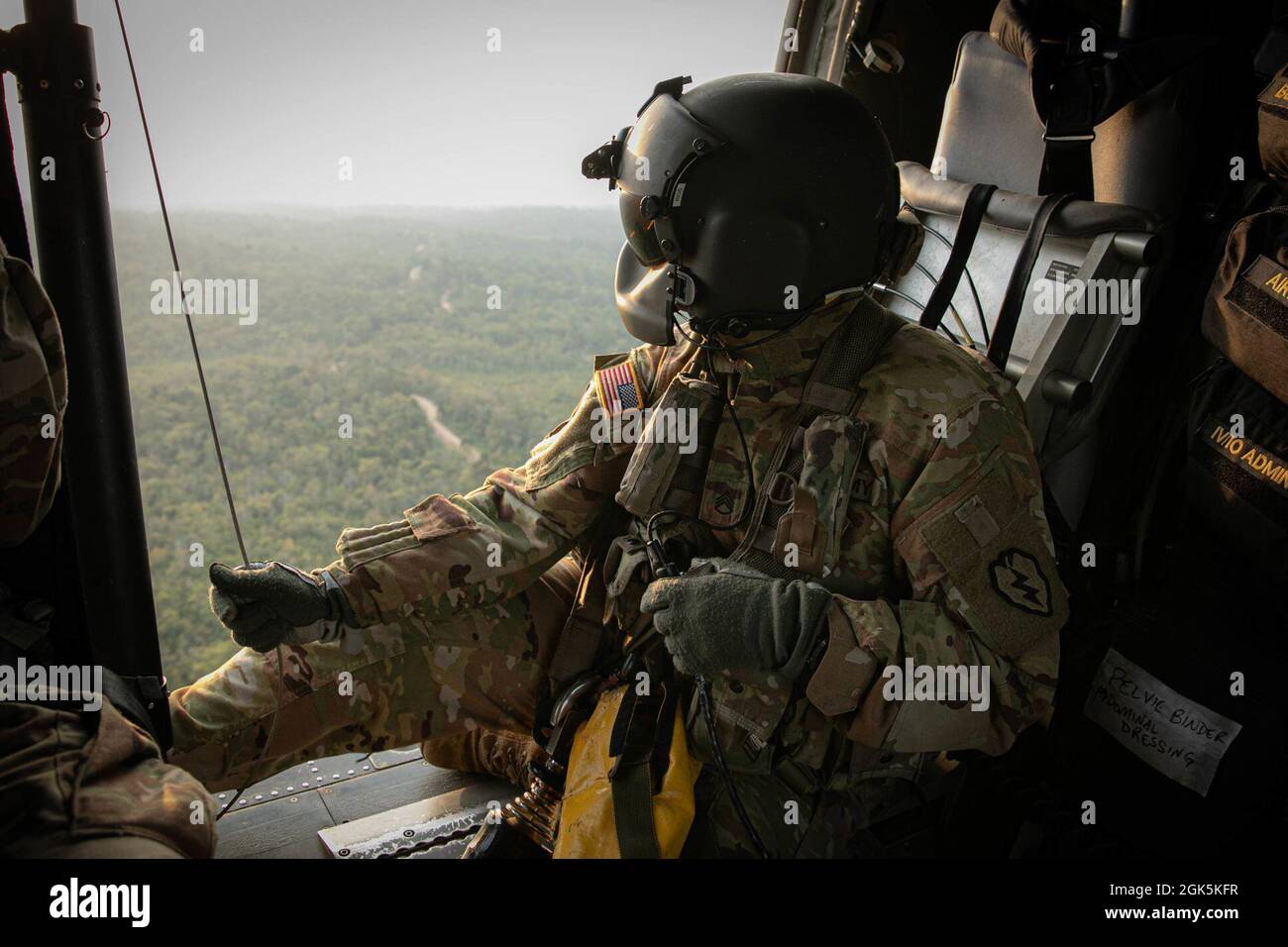 A U.S. Army Flight Paramedic with Task Force Diamond Head, 25th Aviation Regiment, looks out of a HH-60 Blackhawk while holding a Jungle Penetrator, a tool used to extract ambulatory casualties from heavily forested areas, at Baturaja Training Area, Indonesia, on August 9, 2021. Garuda Shield 21 is a two-week joint-exercise between the United States Army and Tentara Nasional Indonesia (TNI-AD Indonesia Armed Forces). The purpose of this joint-exercise is to enhance and enrich the jungle warfare ability of both the U.S. Army and Indonesian Army. Stock Photo