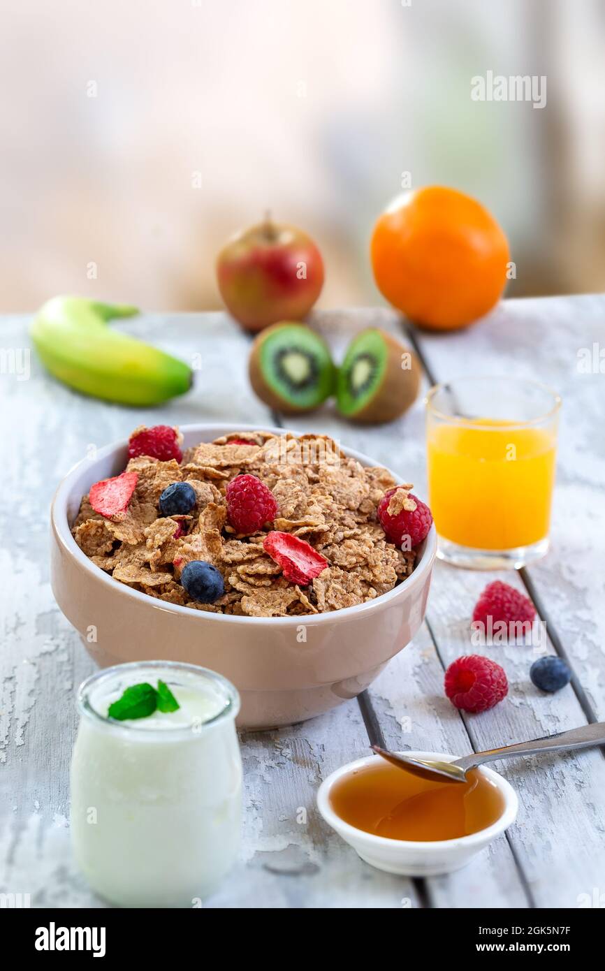 Healthy breakfast with bowl of cereal, orange juice, milk, and fruits