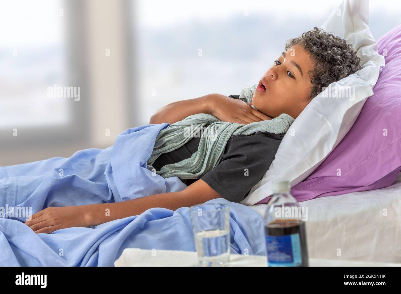 Sick child boy lying in bed with fever, resting at home. Illness kid