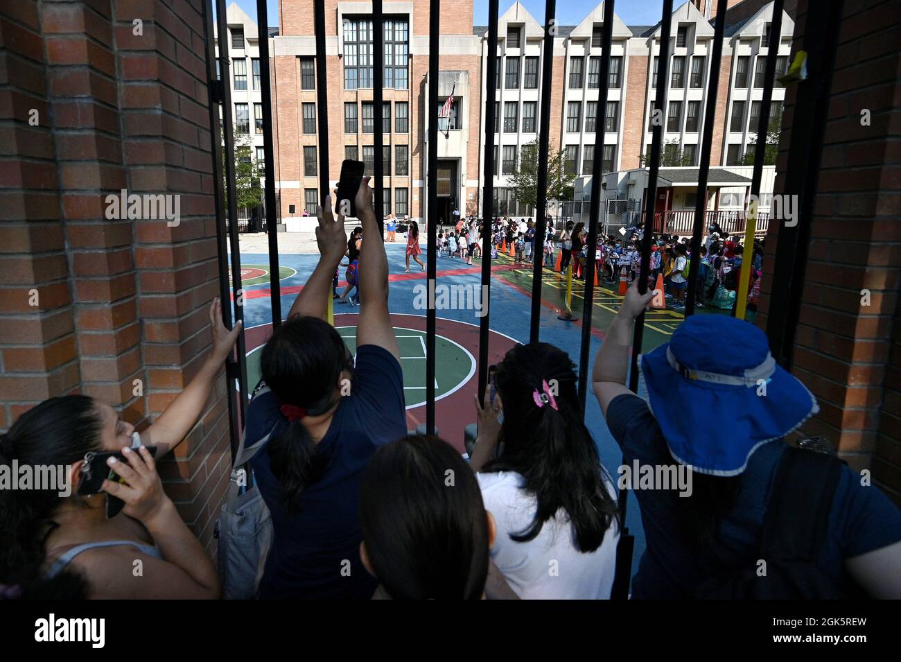 Parents gather at a gate to watch their children go into school as New