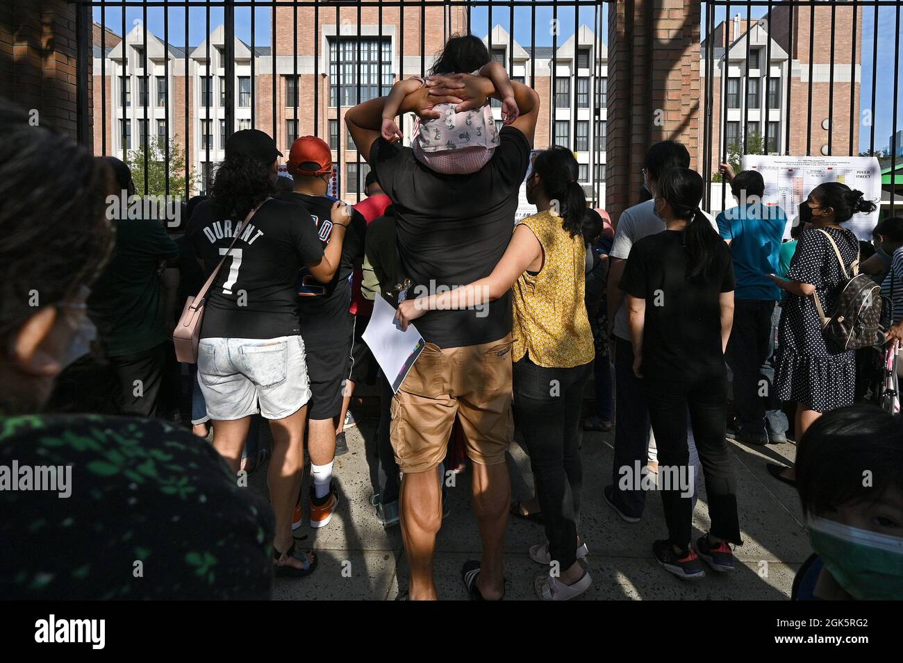 Parents gather at a gate to watch their children go into school as New
