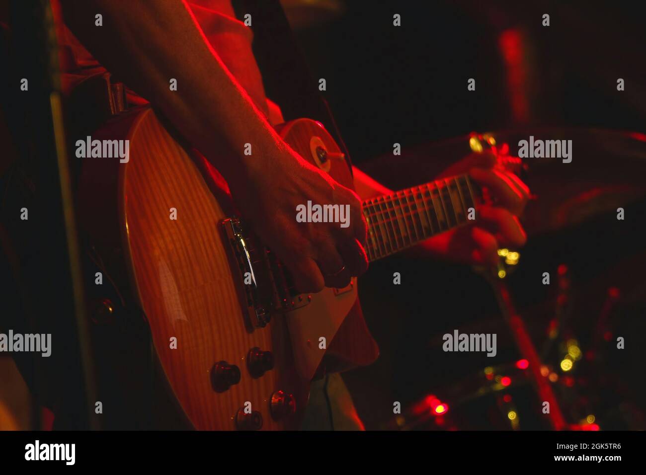 The guitarist plays his guitar in the spotlight. Hands of a guitarist