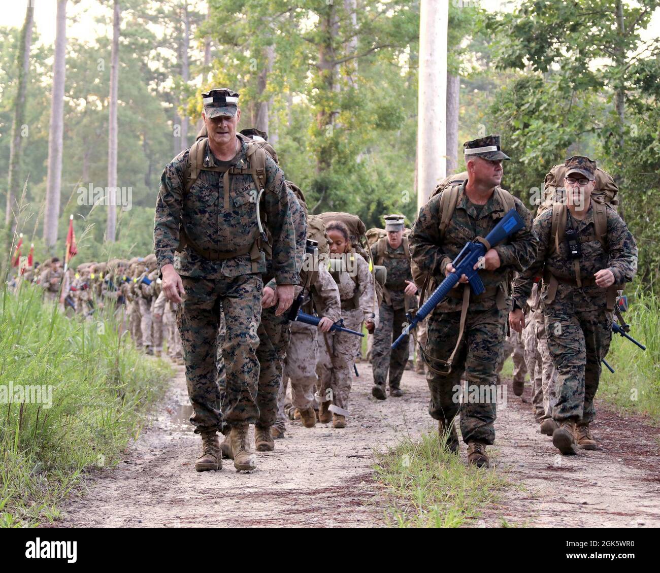 U.S. Navy Capt. Brian Tolbert (left) and Master Chief Petty Officer Jeffrey Pritchett (right) lead sailors attending Field Medical Training Battalion East (FMTB-E) on a four mile hike on Camp Johnson, N.C., Aug. 10, 2021. The sailors conduct increasingly difficult hikes during their training at FMTB-E to build endurance and skills that will be required when serving in Marine Corps units. Stock Photo