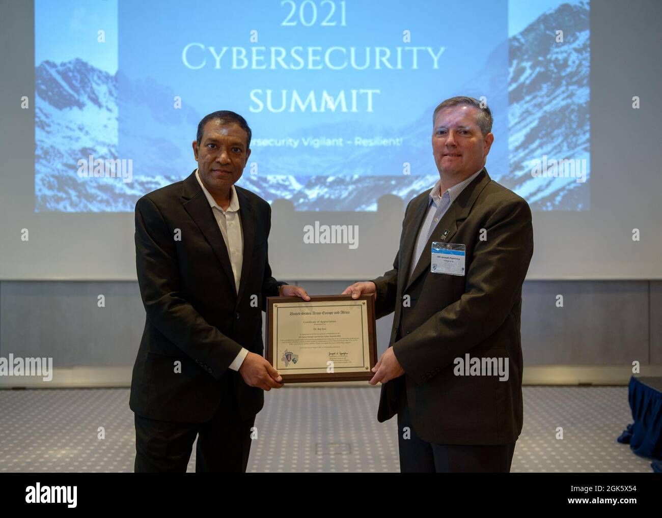 U.S. Army Brig. Gen. Joseph A. Papenfus, Deputy Chief of Staff G6, U.S. Army Europe and Africa (right), presents an award to Dr. Raj Iyer, Army Chief Information Officer, U.S. Department of the Army, during the 2021 cybersecurity summit in Wiesbaden, Germany, Aug. 10-12, 2021. Topics and discussions ranged from covering innovations and challenges to securing cyber terrain objectives. Stock Photo