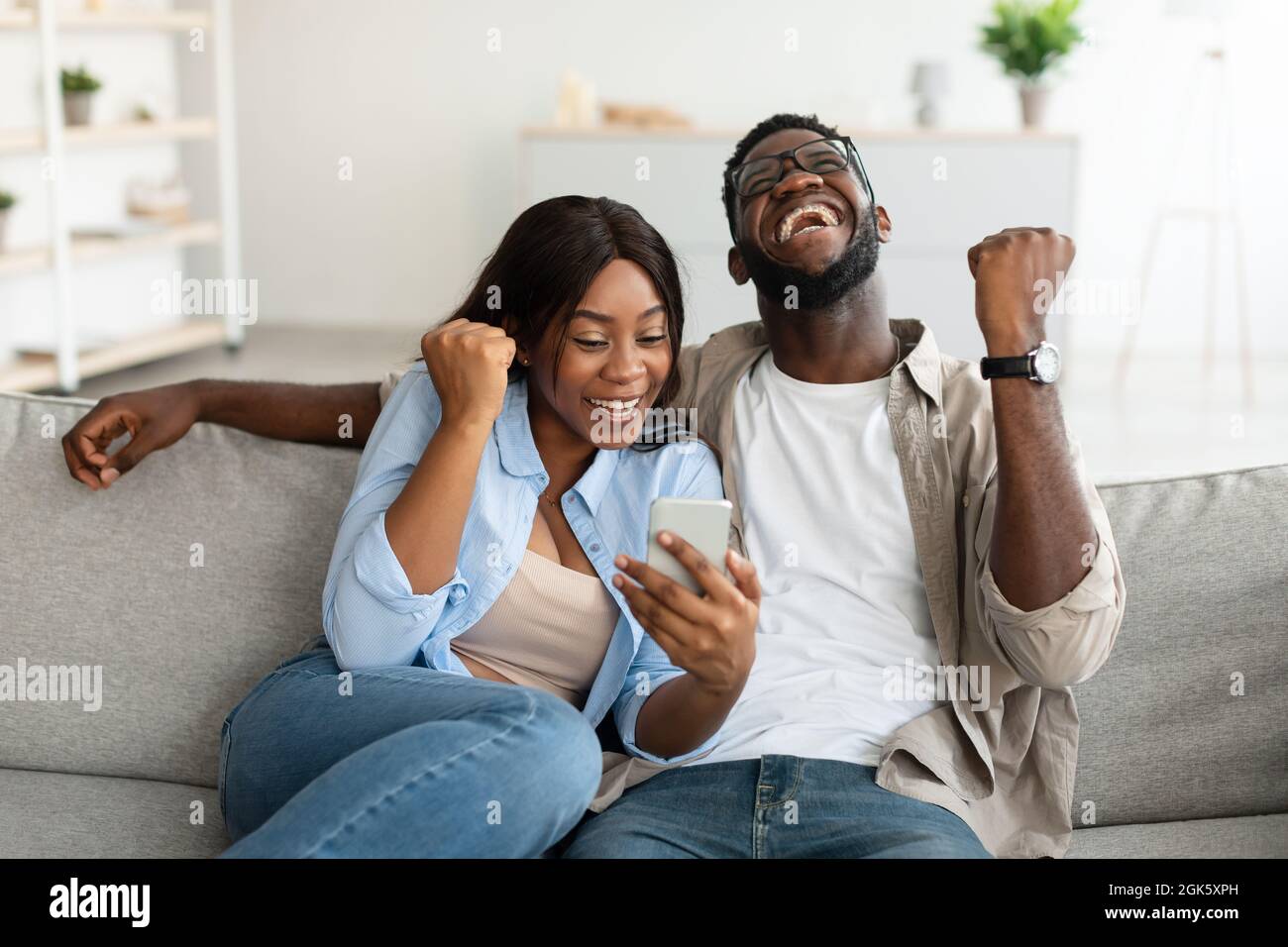 African american couple using smartphone, celebrating win Stock Photo ...