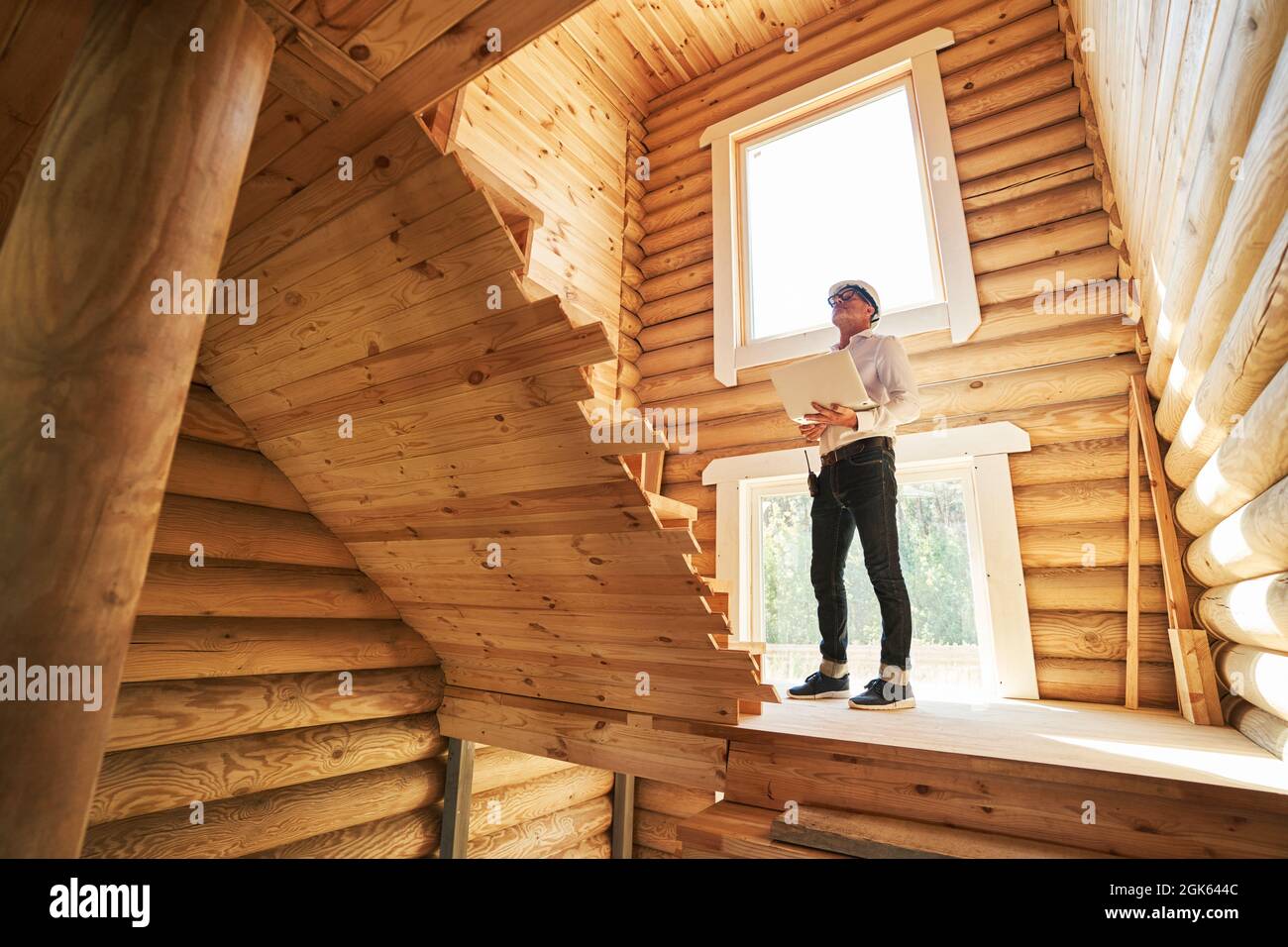 Engineer looking up the stairs while making notes in laptop Stock Photo