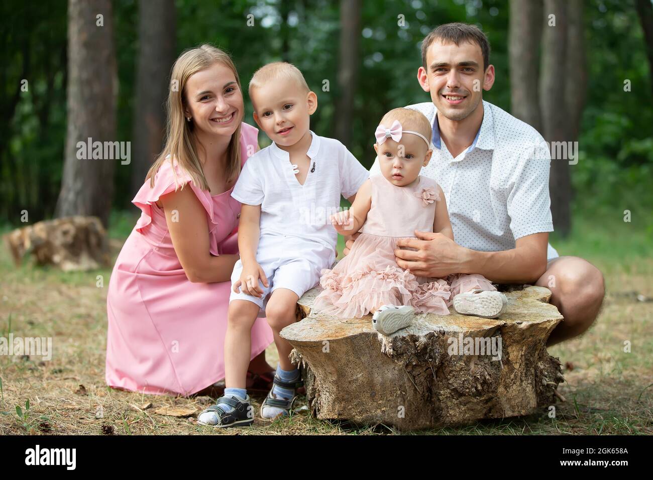 Husband and wife and their little children. Family portrait in nature. Mom  and Dad are posing with their brother and sister. Young family with childre  Stock Photo - Alamy