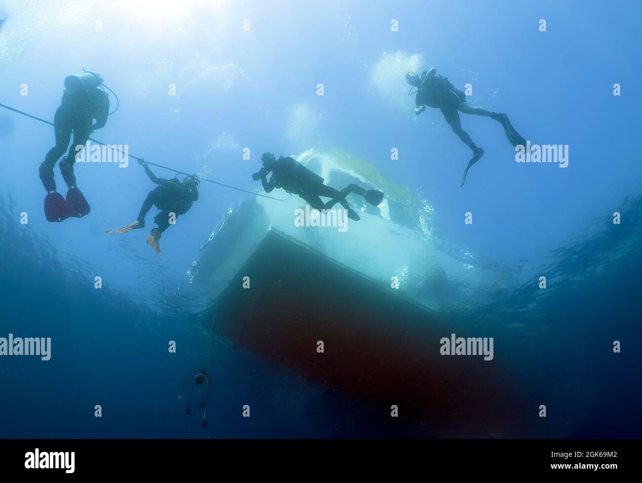 Silhouettes of scuba divers on an ascent line Stock Photo