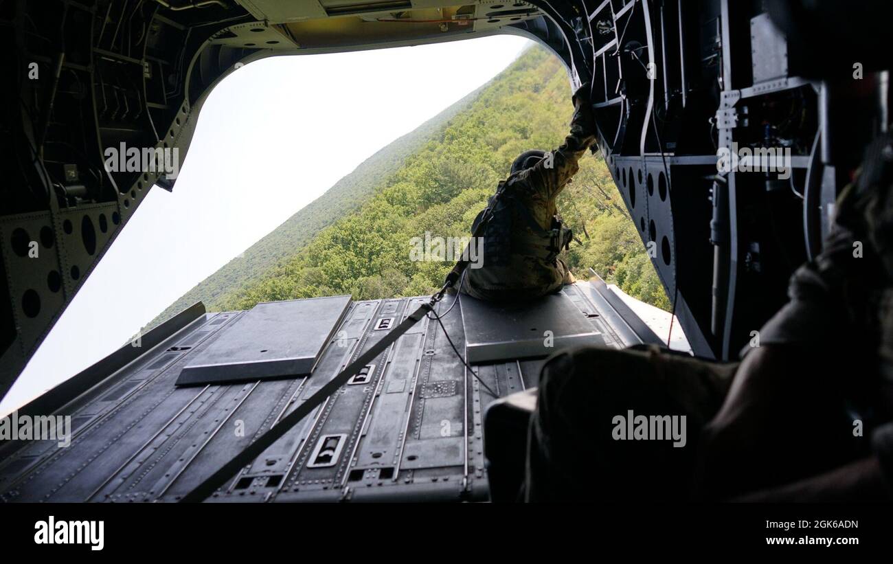 A crew chief watches off the back ramp of the Ch-47 as they airlift the 11B3O Advanced Leader Course to their field training exercise at Fort Indiantown Gap, Pa., on Aug. 13, 2021. Once deployed the Soldiers of the class, led by the cadre from 166th Regiment Regional Training Institute, will be graded on their abilities to lead and community during different scenarios in the field Stock Photo