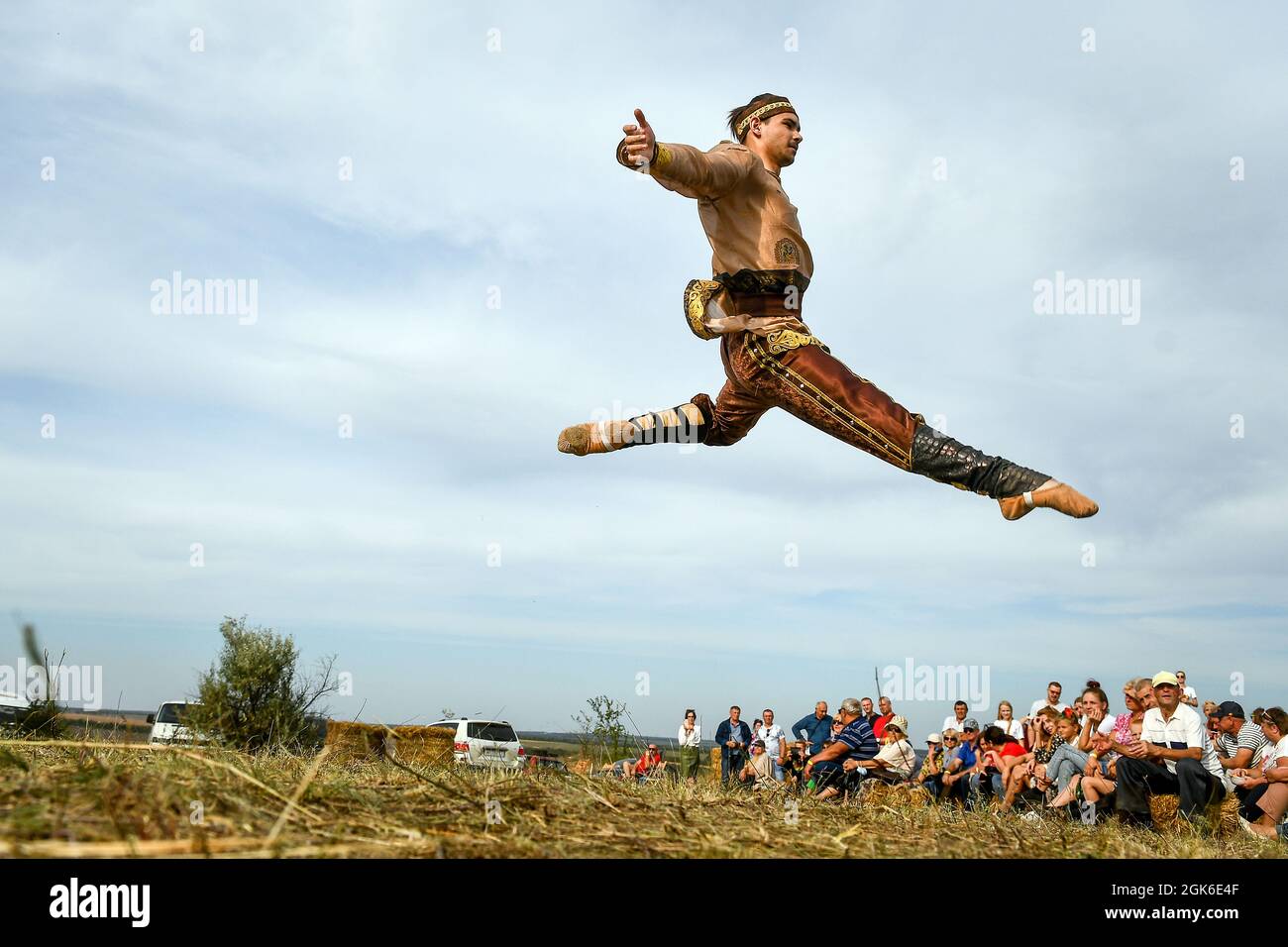 ZAPORIZHZHIA REGION, UKRAINE - SEPTEMBER 11, 2021 - A dancer in a period costume is captured in mid-air man and a woman beat the frame drums during th Stock Photo