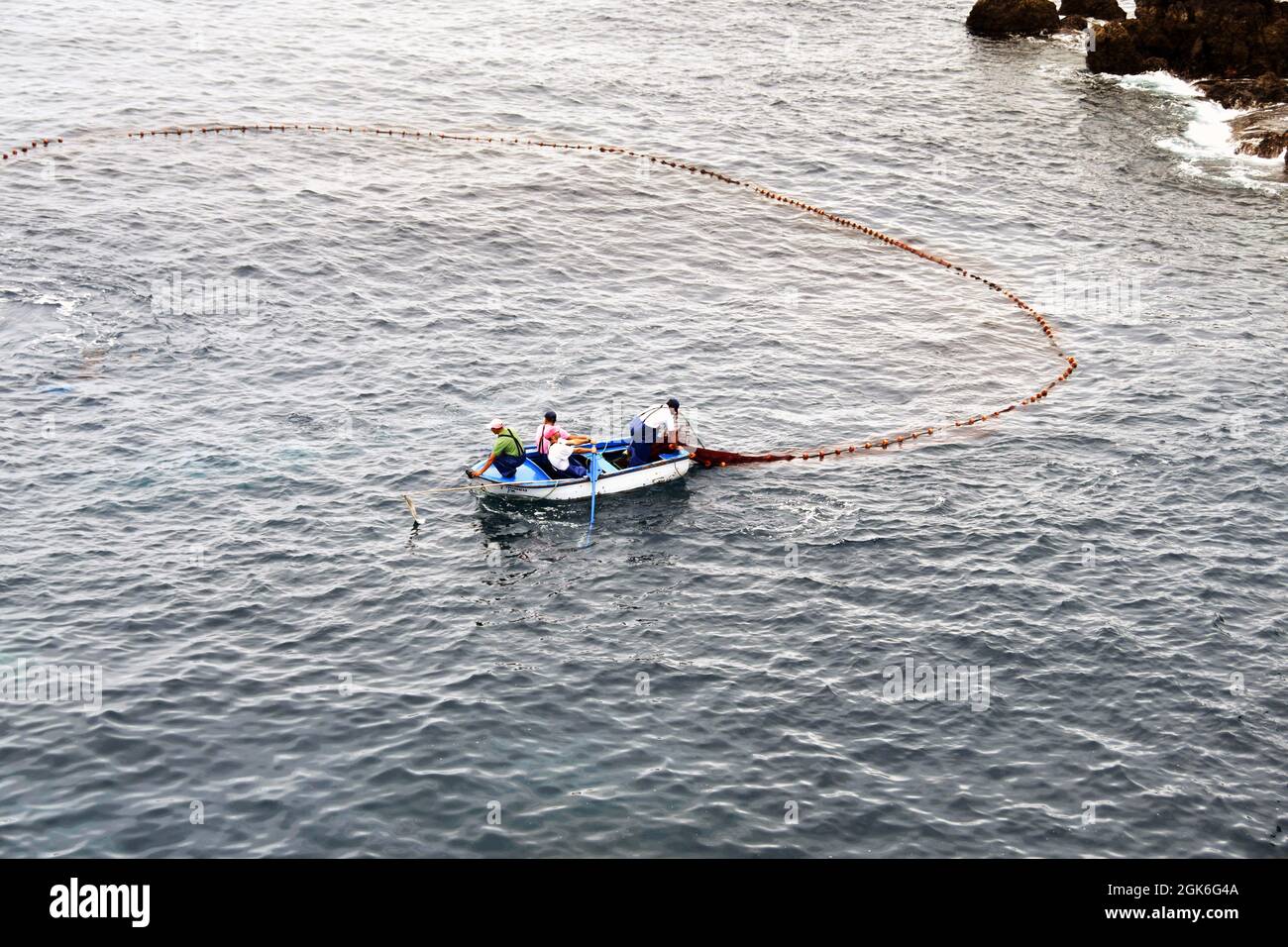 Madeira, Portugal - February 2016: Fishermen on a small rowing boat hauling in a heavy fishing net Stock Photo