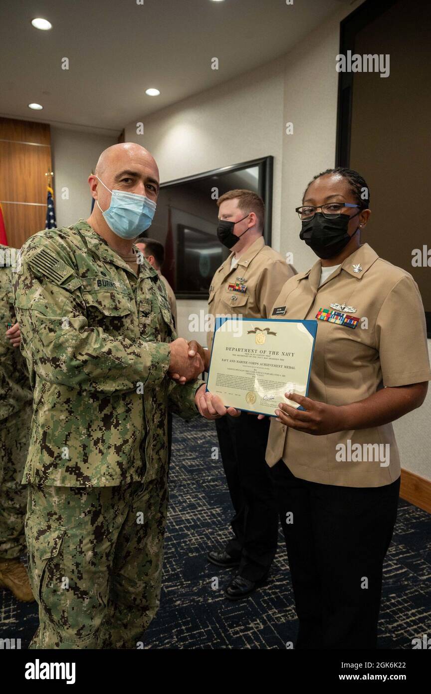 WASHINGTON, DC (Aug. 16, 2021) – Capt. Mark Burns (left), Naval Support Activity Washington commanding officer, presents Logistic Specialist 1st Class Otini Abu (right) with a Navy and Marine Corps achievement medal during an award ceremony held onboard Washington Navy Yard. Stock Photo