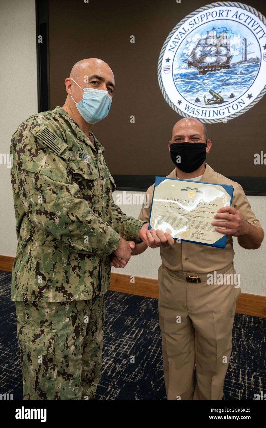 WASHINGTON, DC (Aug. 16, 2021) – Capt. Mark Burns (left), Naval Support Activity Washington commanding officer, presents Chief Navy Counselor Eduardo Rivera (right) with a Navy and Marine Corps commendation medal during an award ceremony held onboard Washington Navy Yard. Stock Photo