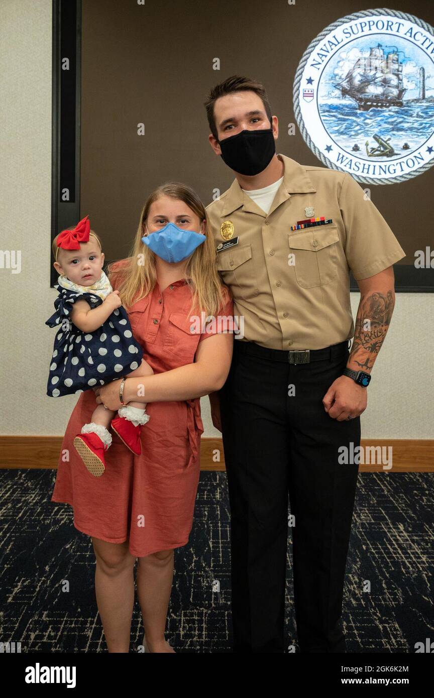 WASHINGTON, DC (Aug. 16, 2021) – Master-at-Arms 3rd Class Griffin Hahn, right, poses with family members before an award ceremony held onboard Washington Navy Yard. Stock Photo