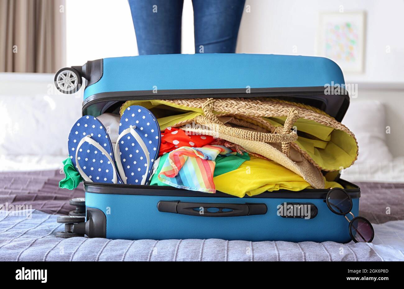 Open heavy suitcase with different personal stuff on bed. Luggage