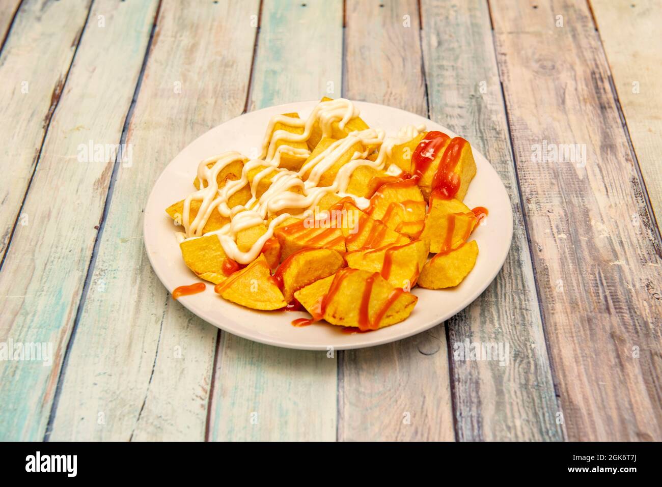 Diced fried potatoes with brava sauce and aioli cooked in a tapas bar in  Madrid on a wooden background Stock Photo - Alamy