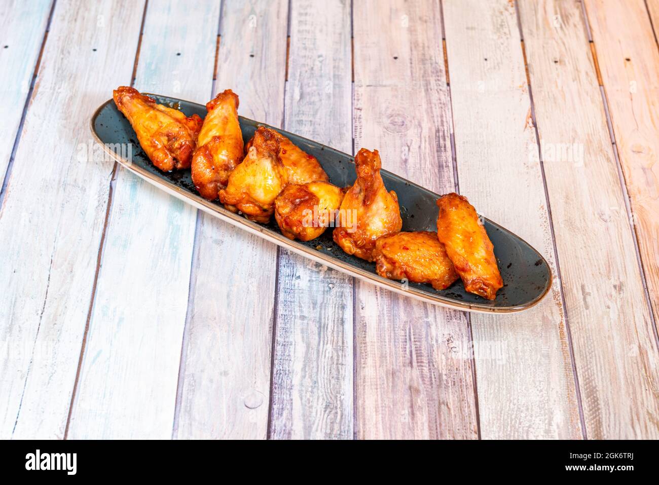elongated tray with portion of fried chicken wings on the barbecue on wooden table Stock Photo