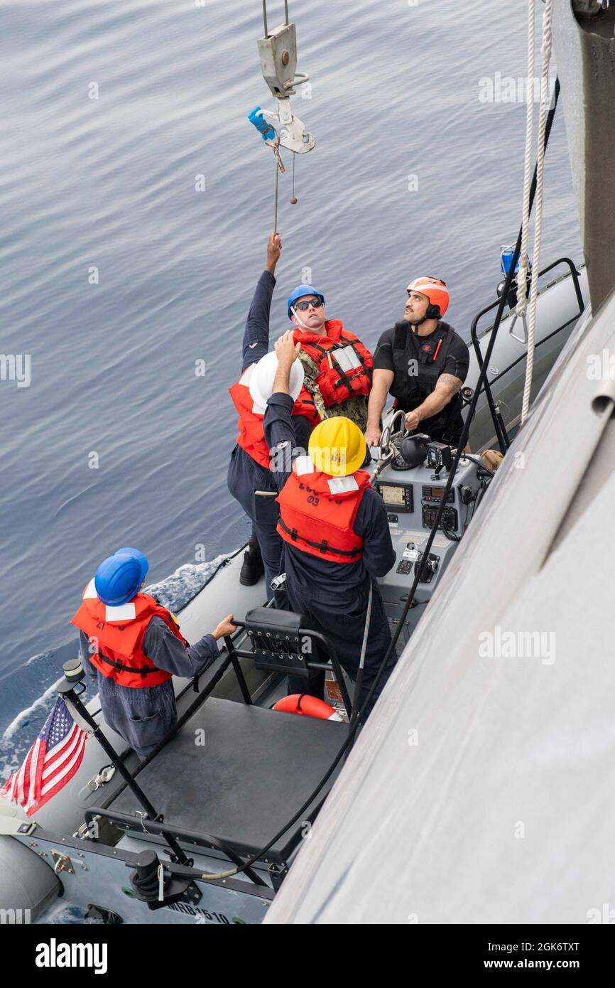 210818-N-WU807-1050 SOUTH CHINA SEA (Aug. 18, 2021) Sailors reach for the boat hook in a rigid-hulled inflatable boat during boat operations aboard Independence-variant littoral combat ship USS Charleston (LCS 18), Aug. 18. Charleston, part of Destroyer Squadron Seven, is on a rotational deployment, operating in the U.S. 7th fleet area of operations to enhance interoperability with partners and serve as a ready-response force in support of a free and open Indo-Pacific region. Stock Photo