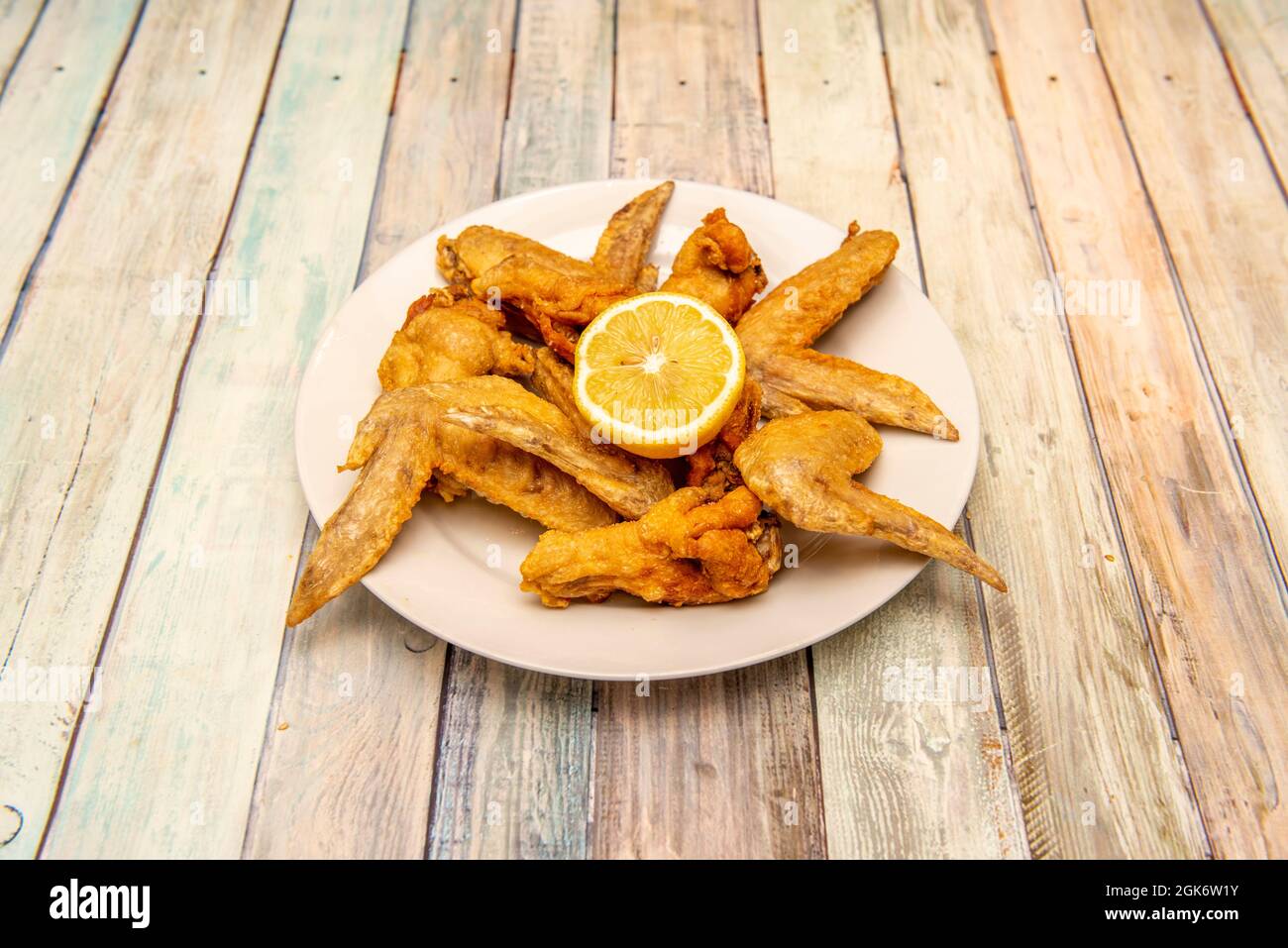 Fried chicken wings in the kitchen of a Spanish tapas restaurant on vintage wooden table Stock