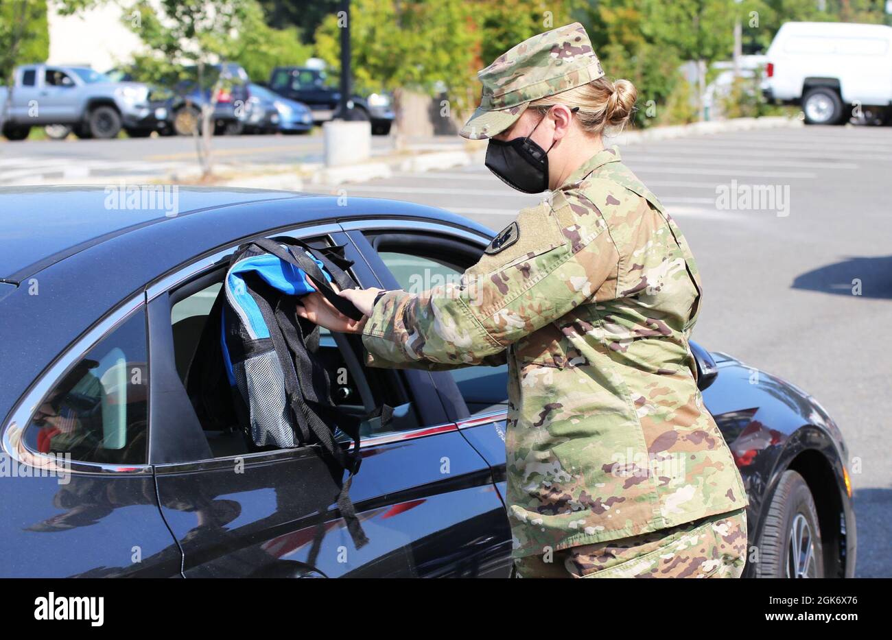 1st Lt. Lexis Jones, Education Officer with the Washington Army National Guard places a backpack filled with supplies and resources into a car during the Joint Service Support back to school resource event on Camp Murray, Wash, August 18, 2021. The JSS was able to provide 1,600 backpacks to National Guard children during the seven events. Stock Photo