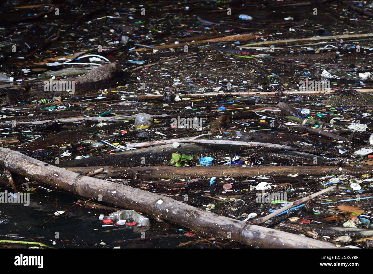 close up of a polluted water river full of floating plastics, gasoline