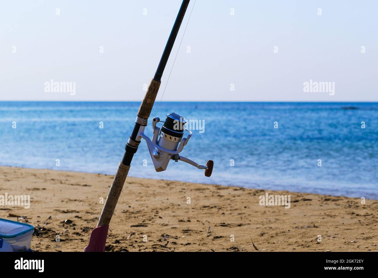 Fishing rod with spinning reel on beach. Saltwater fishing on sea
