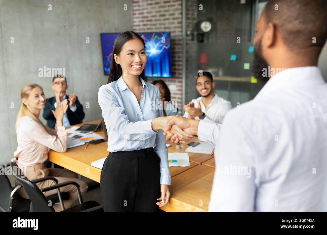 Black Boss Shaking Hands And Congratulating Asian Female Employee With Business Success Stock Photo