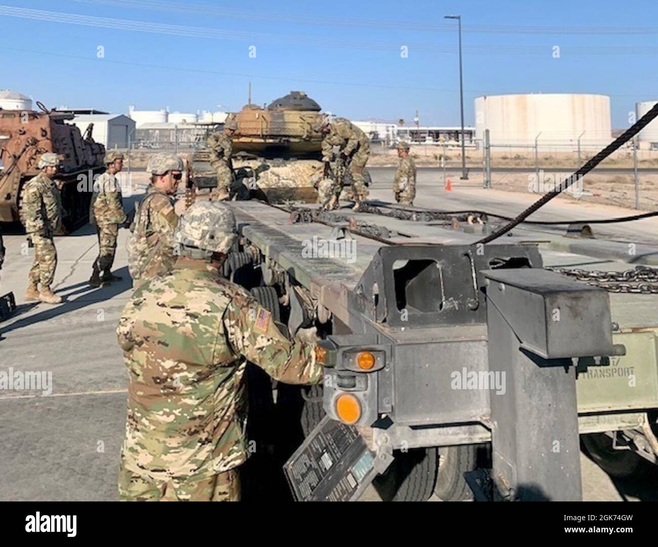 257th Transportation Company (CBT HET) Soldiers disconnect winch cables and adjust level on the M1000 semi-trailer after removing a M60 tank. Stock Photo
