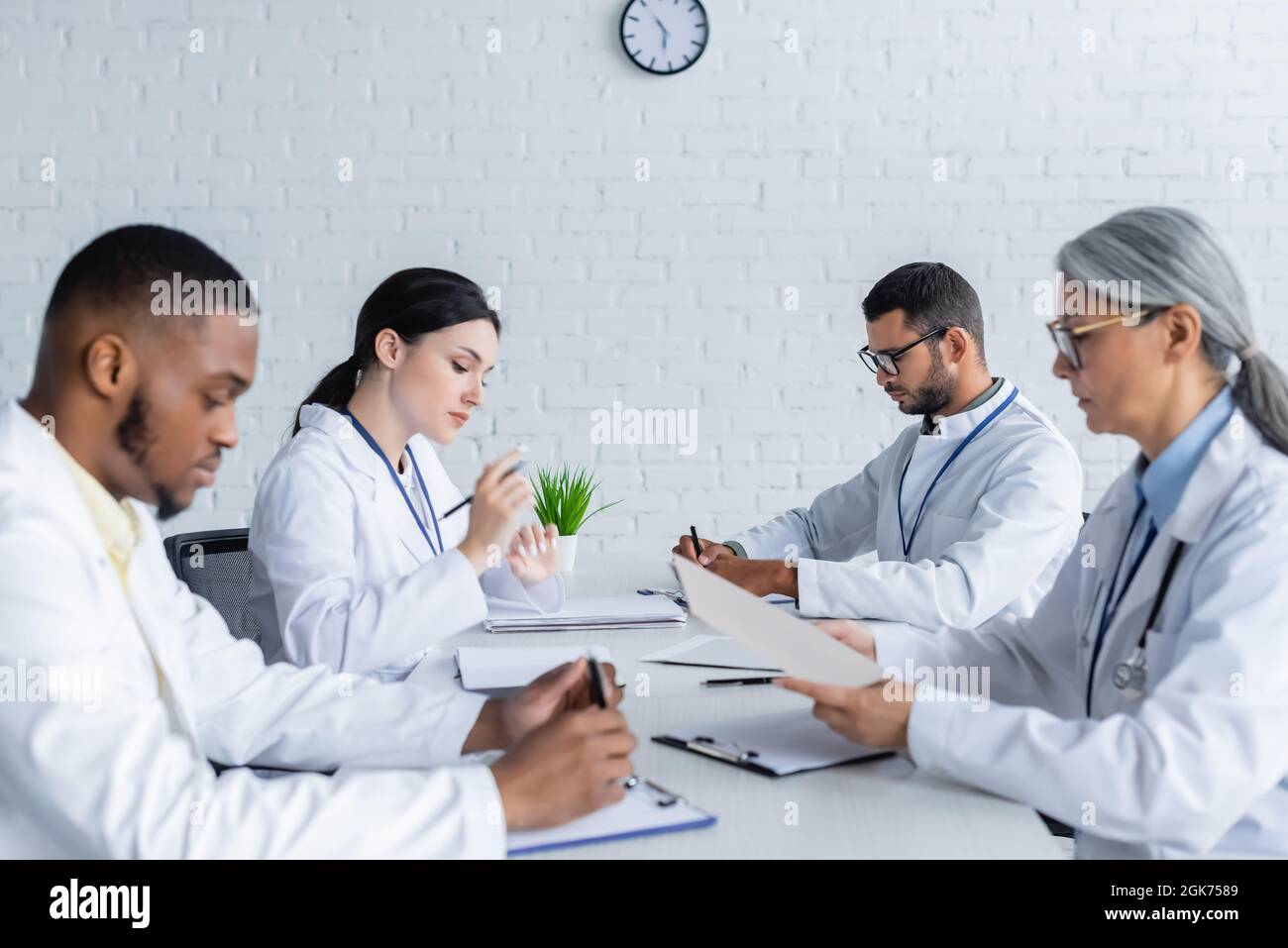 multicultural doctors sitting at desk during medical council in clinic ...