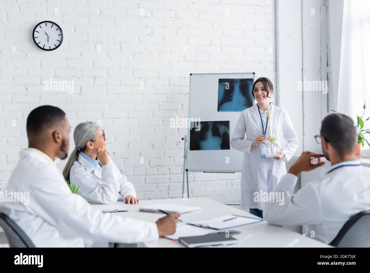smiling doctor standing near flip chart with lungs x-rays and showing ...