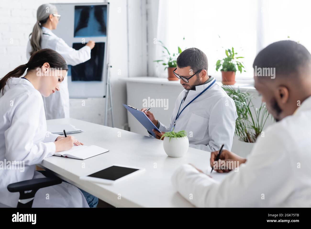 mature doctor near flip chart with lungs x-rays and multiethnic ...